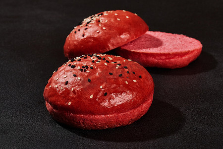 新鲜可口的烤红面包，在黑色背景上撒上深色和白色的芝麻，并带有复制空间。