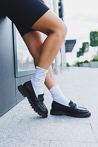 穿皮鞋的女性腿、白色袜子和黑色莫卡辛鞋、黑色短裤、时尚细节