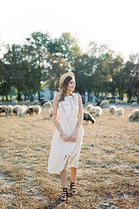 戴草帽的女孩站在草坪上放牧羊