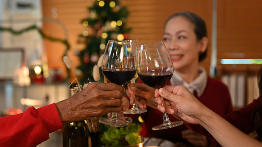 家人在圣诞晚餐上敬酒，专注于手和酒杯。