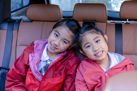 汽车驾校摄影照片_两个快乐的学生微笑着享受汽车公路旅行。