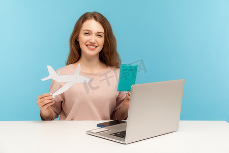 签证飞机摄影照片_在蓝色背景上使用笔记本电脑的情感年轻女子。