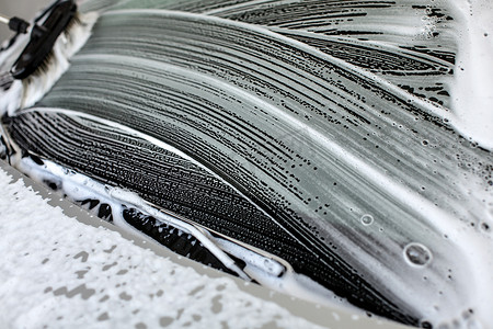 在自助洗车场洗车的挡风玻璃上留下洗发水和泡沫的刷子。