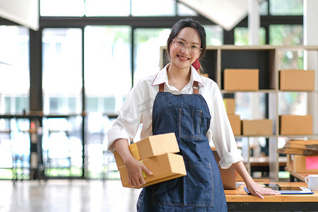 亚洲年轻女性在家里用盒子工作的肖像 workplace.start-up 小企业主、小企业企业家 SME 或自由职业在线和交付概念。