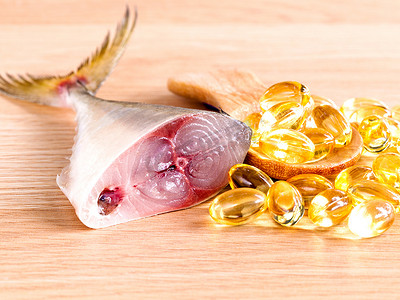 新米摄影照片_木勺上的 Omega 3 鱼油胶囊与新鲜鱼 se