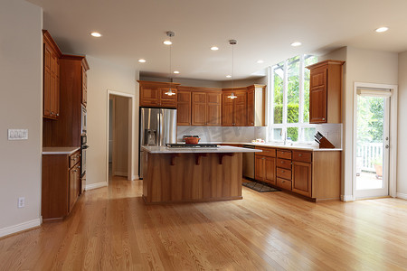 改造后的家中厨房配有岛台、内置炉灶、吊灯、橡木硬木地板和不锈钢器具