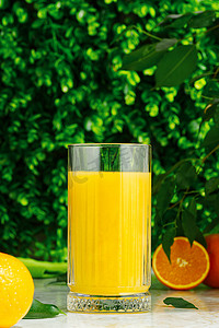 绿色背景下的一杯新鲜橙汁和新鲜水果