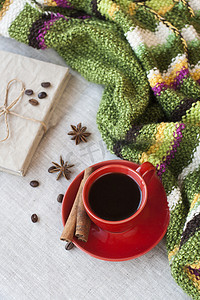 新鲜美味的热浓咖啡，红色杯子里放着咖啡豆，浅色背景上放着一本工艺笔记本。