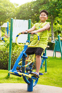 快乐的亚洲运动男孩在花园的秋千操场上玩耍。