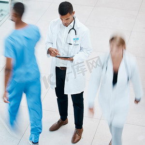 医生患者平板电脑摄影照片_繁忙的医院，医生在平板电脑上浏览测试结果、患者记录和医学研究。