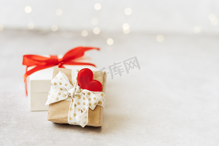有红色弓和心脏形状的礼物或礼物盒在光背景。