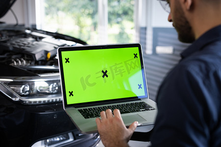 汽车服务技工使用带绿屏模拟色度键汽车诊断软件的笔记本电脑。