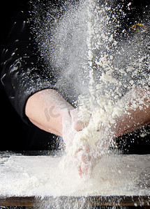 灰尘摄影照片_黑色制服的厨师在不同的 d 中撒上白小麦面粉