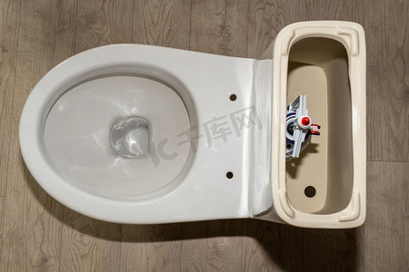 厕所标语冲水摄影照片_白色马桶水箱，带有打开的盖子和冲水系统。