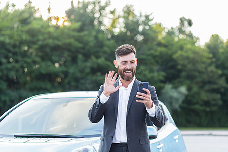 快乐的商人汽车推销员通过视频通话在线检查汽车，并在电话上申请，一个男人卖车很开心