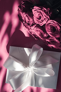 豪华假日丝绸礼盒和粉色背景玫瑰花束、浪漫惊喜和鲜花作为生日或情人节礼物