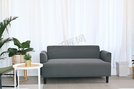 明亮的客厅内部配有舒适的沙发、白色桌子和室内植物。