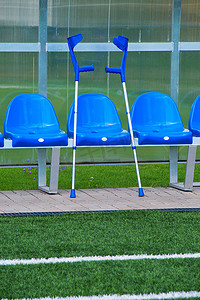 室外体育场球员长凳上有新的蓝色塑料座椅，透明塑料屋顶下有新油漆的椅子。