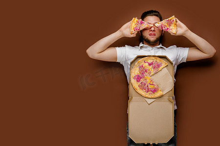 年轻英俊的白人男子躺着，拿着两块披萨闲逛。