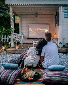 情侣晚上在花园里看电影，人们在花园里看电影，晚上在家看花园电影院