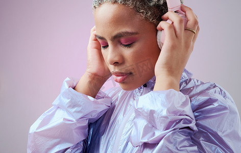 时尚、耳机和黑人女性在工作室粉红色背景下穿着复古蒸汽波衣服听音乐。 