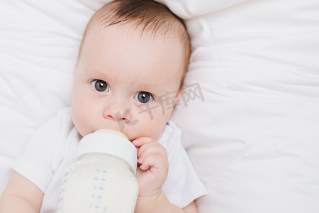 婴儿床上的婴儿用奶瓶吃东西。