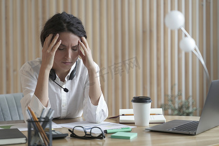 西班牙女摄影照片_疲惫的西班牙女商人闭着眼睛坐在办公室的工作场所，头痛