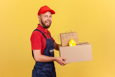 身穿制服、头戴红帽的送货员拿着纸箱和纸屋上门送货。
