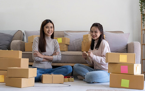 开办小型企业的 SME 所有者的肖像，两名亚洲女性查看在线订单销售产品与箱子一起在家办公室自由工作，中小企业在线中小企业