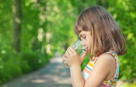 一个孩子在大自然中喝一杯水。