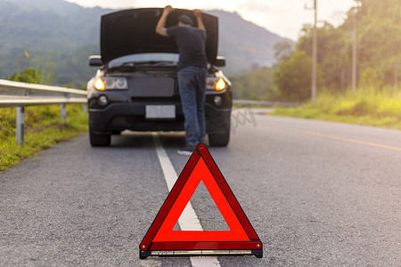 道路故障摄影照片_道路上的红色三角形标志警告车辆发生故障