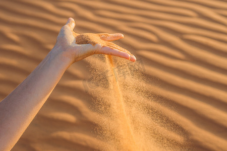 手指天空摄影照片_沙子从沙漠中女人的手指间滑过