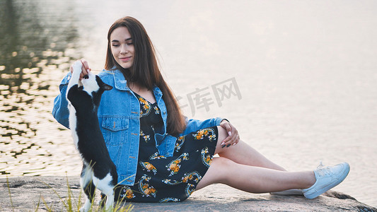 一个女孩和猫的摄影照片_一个女孩在湖边和一只猫玩耍。