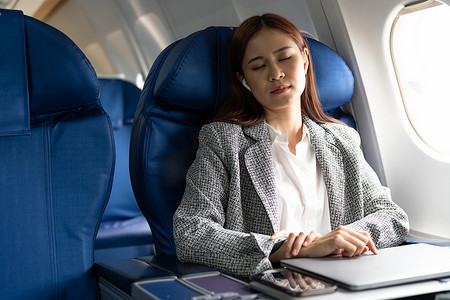 乘飞机旅行时，疲惫的亚洲商务女士在座位上打盹。
