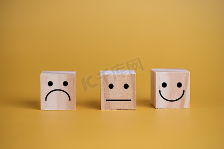 客户服务和满意度概念快乐笑脸图标。业务反馈积极评价给桌子上的木立方体留下了深刻的印象。