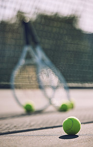白天，在一家体育俱乐部的空场上，一组网球和球拍对着网。