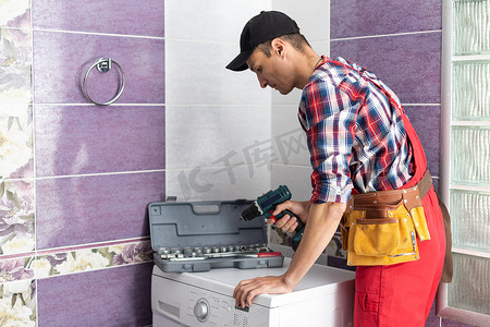 穿着工作服的水管工正在修理房子里的洗衣机。