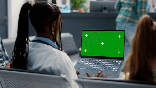 全科医生在候诊室拿着带绿屏的笔记本电脑