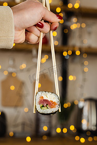 拿着寿司卷在新年灯光背景上。