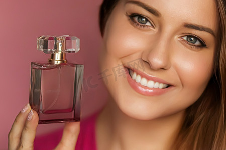 粉红色背景的香水、美容产品和化妆品模特脸部肖像，美丽的女人拿着带有花卉女性香味、时尚和化妆的香水瓶
