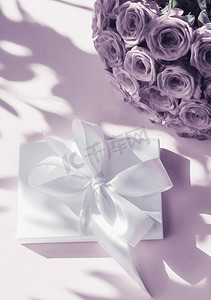 玫瑰礼盒摄影照片_豪华假日丝绸礼盒和紫色背景的玫瑰花束、浪漫惊喜和鲜花作为生日或情人节礼物