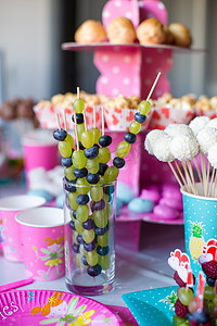 生日聚会上甜蜜儿童餐桌上的水果小食、白巧克力蛋糕棒棒糖和爆米花