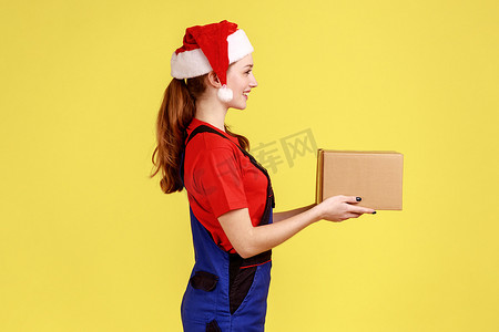 邮政寄递摄影照片_快递女性为客户递纸板包裹的侧视图肖像，新年礼物。