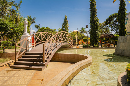 一个平静的公园的景色，喷泉上有一座小木桥。