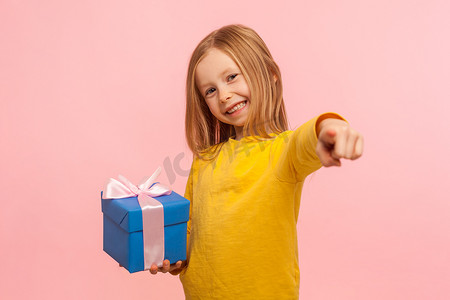 善良慷慨的小女孩的肖像，拿着礼盒、奖金、手指指向相机