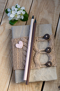 旧复古记事本米色针织毛衣，心形毛毡和木制背景铅笔。