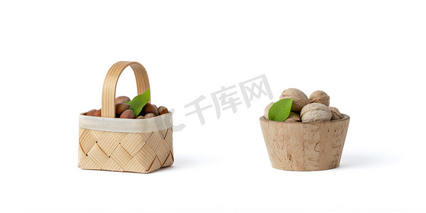 不同品种摄影照片_不同品种的核桃和榛子放在白色孤立背景的木碟和篮子里。