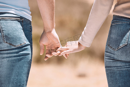 情侣牵着手摄影照片_深情的情侣牵着手，在大自然中表现出爱、关怀和联系。