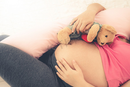 孕晚期摄影照片_快乐的孕妇睡在卧室的床上。
