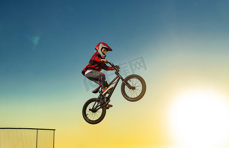 一轮太阳摄影照片_一名青少年 BMX 赛车手在滑板公园的泵道上表演特技。